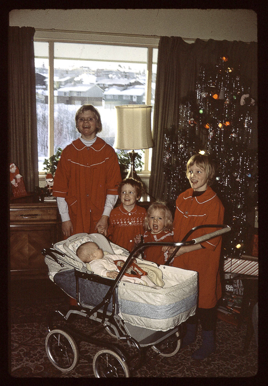Five girls in matching red pajamas by the Christmas tree with a baby in a pram, Kitimat