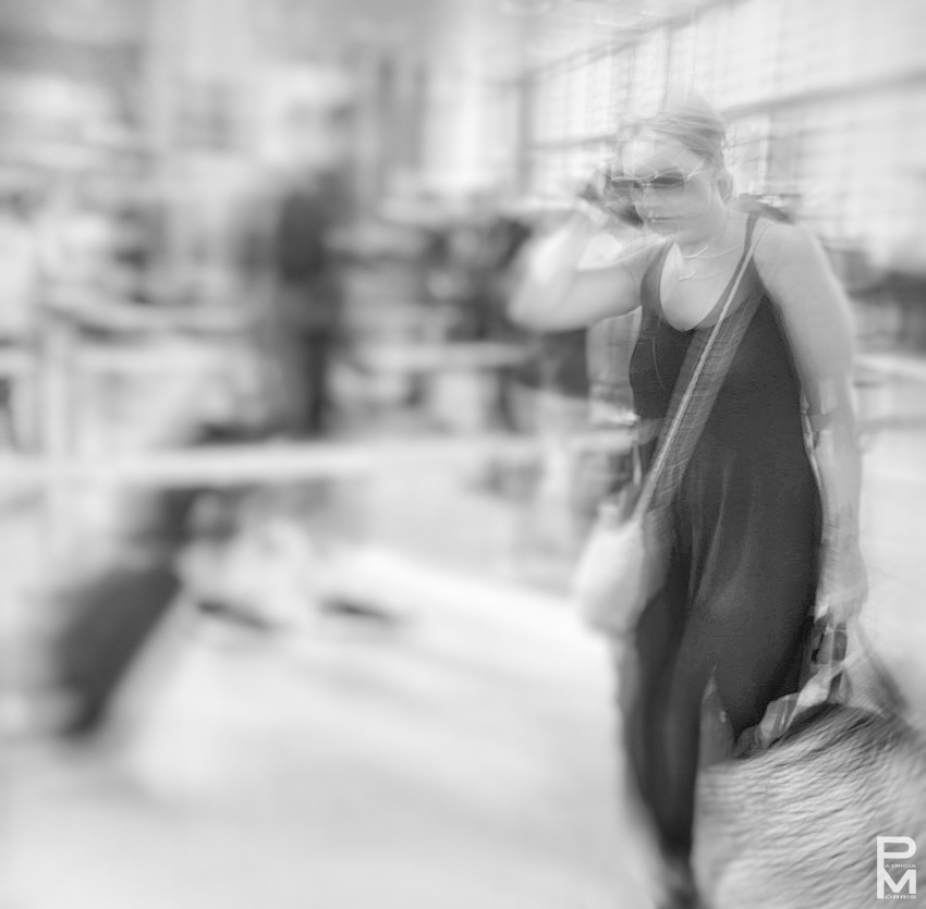 ICM digital photograph taken at an airport of a woman carrying a bag and talking on her cellphone, In Transit