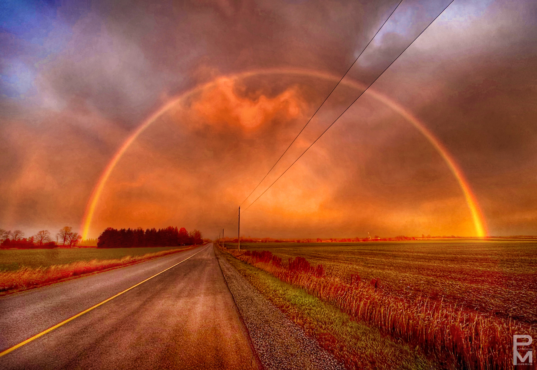 Double rainbow over a country road at sunset