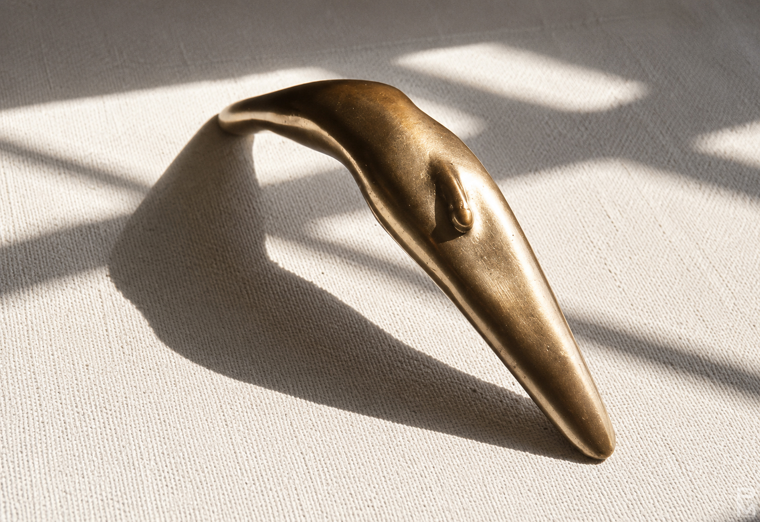 Bronze sculpture of a male figure arching his back, referencing a handle and a weapon.
