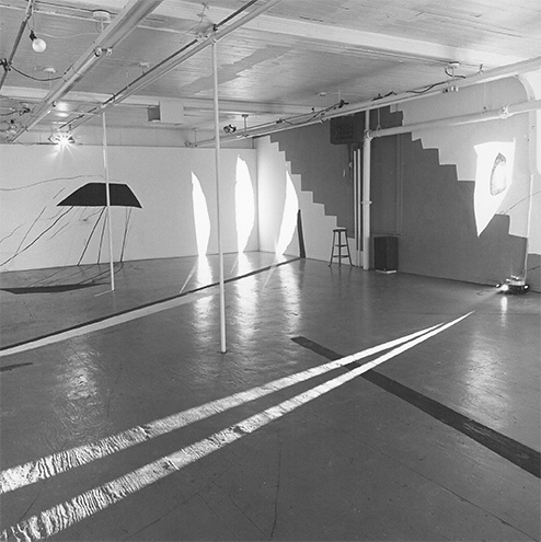 Black and white view of ART PLAY II installation with painting on the gallery walls, floor and ceiling and geometric light projections across the gallery floor.