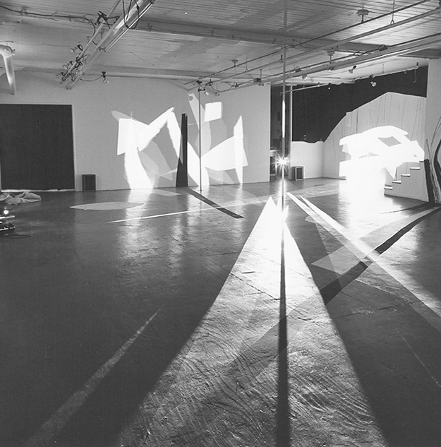 Black and white view of ART PLAY II installation with painting on the gallery walls, floor and ceiling and geometric light projections across the gallery floor.