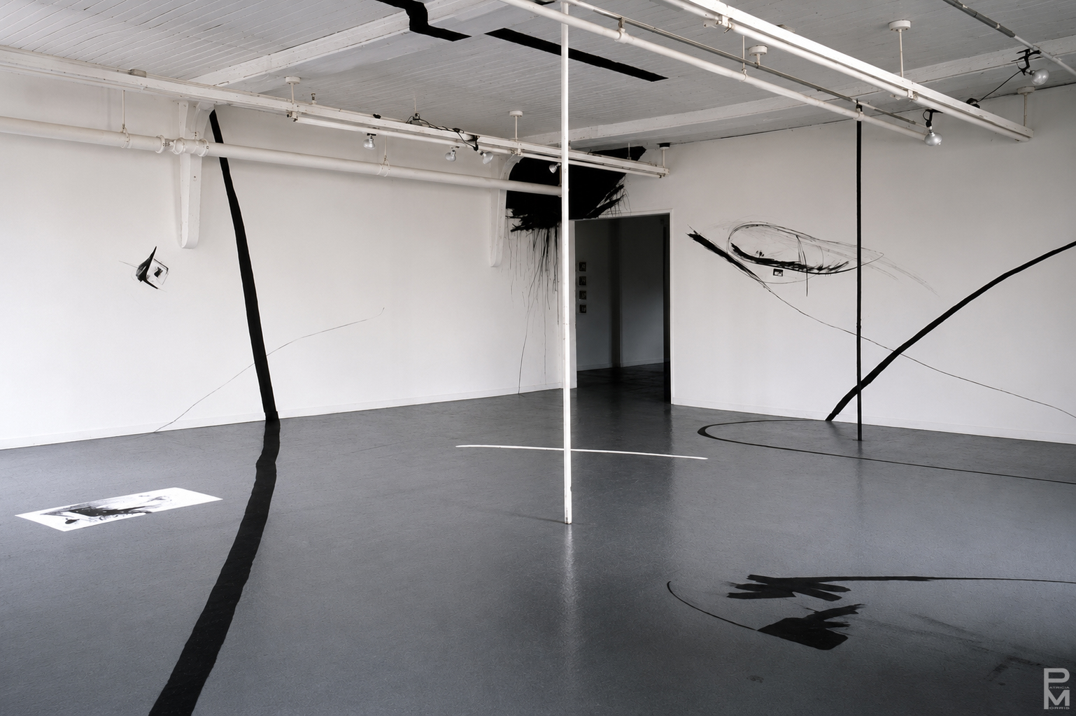 Black and white view of ART PLAY installation with painting on the gallery walls, floor and ceiling and geometric light projections across the gallery floor.