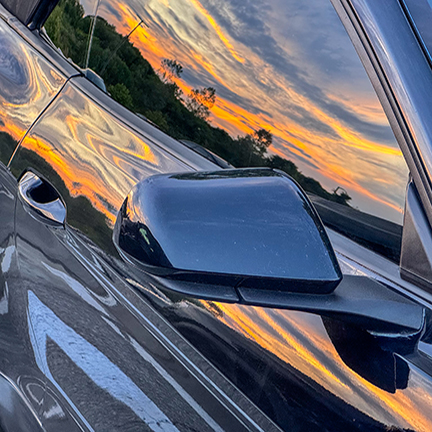 Sunset reflected in a car's side mirror and window