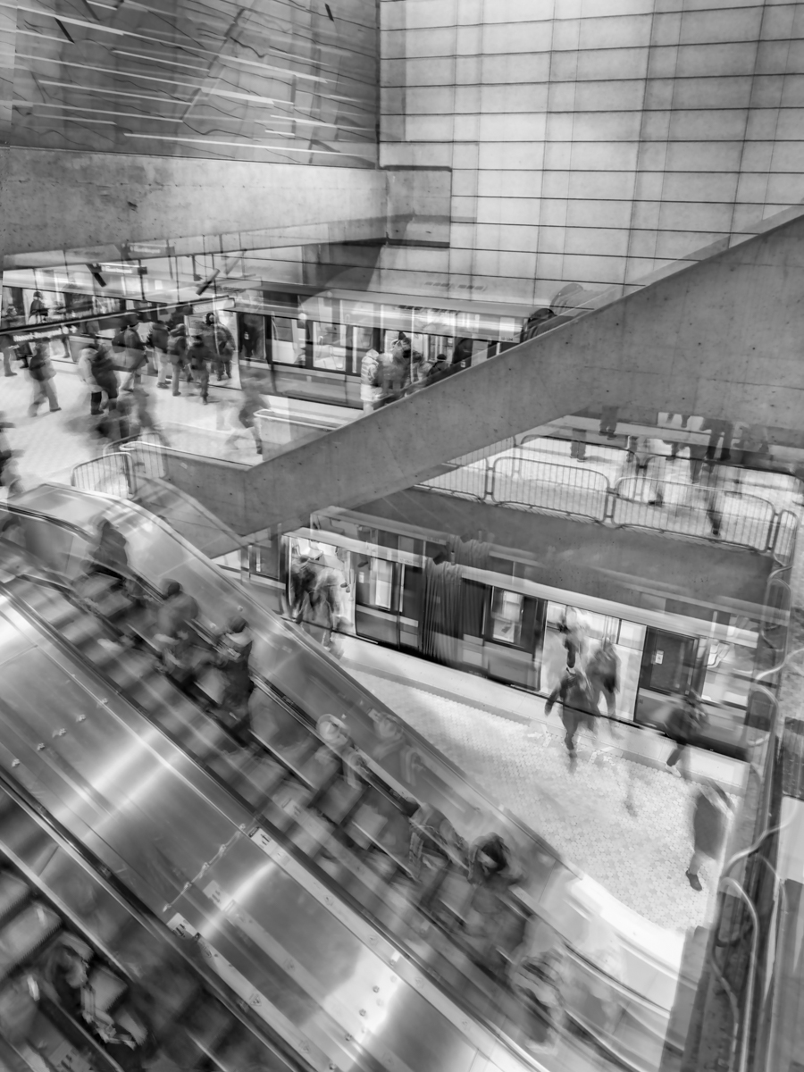 Black and white multiple-exposure photograph of commuters on an escalator and train platform, Lionel-Groulx metro station
