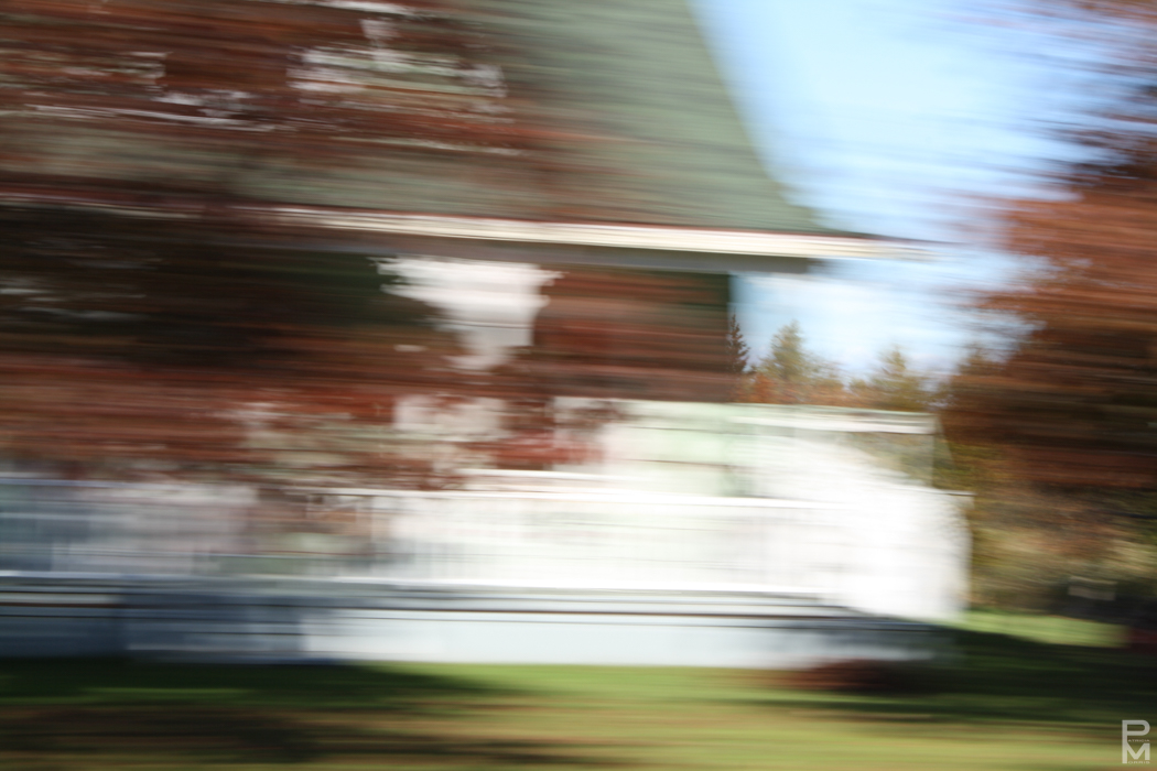 Motion-blurred photo of a house with autumn trees, taken from a moving vehicle