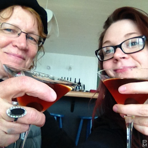 Two people toasting with dark cocktails in martini glasses