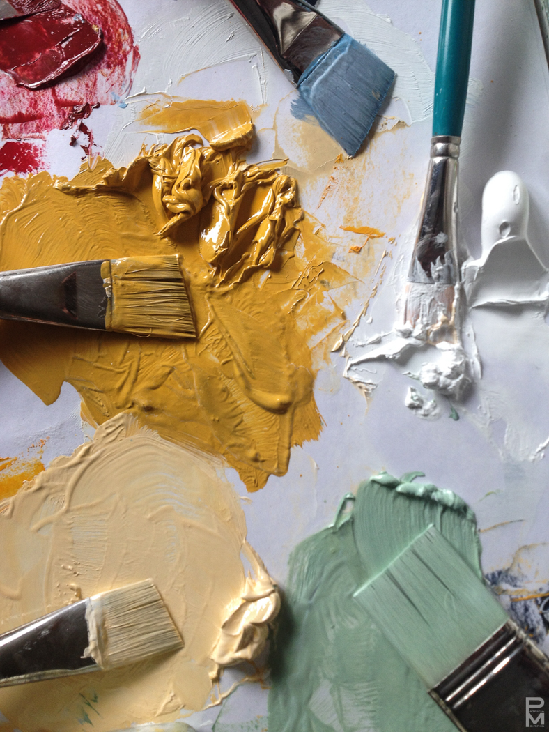A painter's palette loaded with mixed colour and brushes