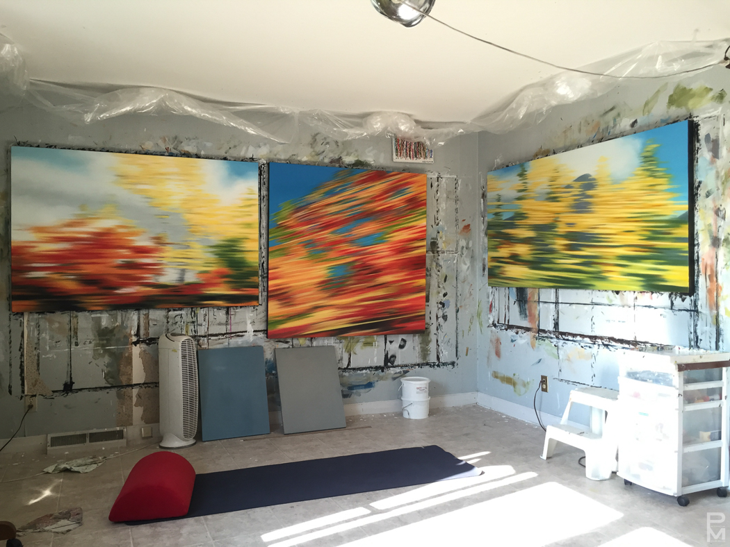 Three large finished motion-blur paintings hanging on a paint-splattered studio wall