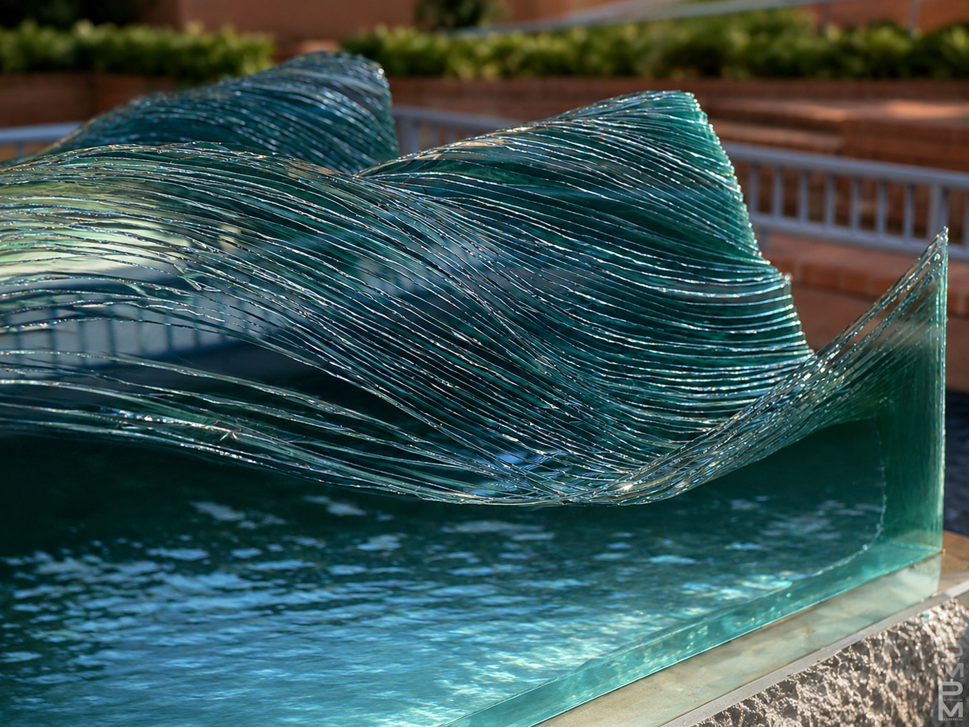  Detail of sculpture made of stacked pieces of glass, depicting a wave installed in a grassy yard